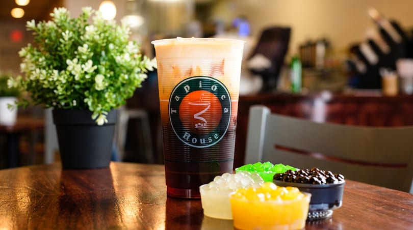Tapioca House layered bubble tea with colorful boba and jellies on a wooden table.