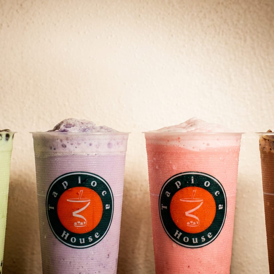 Four colorful Tapioca House bubble teas: green with boba, purple, pink, and chocolate with jelly.