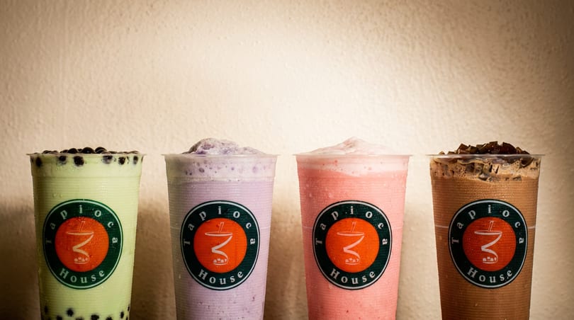 Four colorful Tapioca House bubble teas: green with boba, purple, pink, and chocolate with jelly.